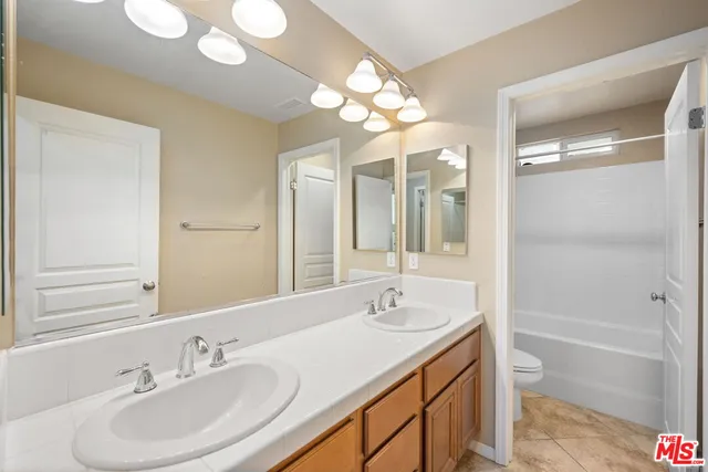 a bathroom with a sink a toilet and a large mirror