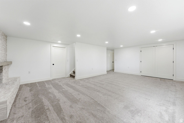 871 Bonita Way Centerville, UT 84014 - Photo 27 of 61 Spacious room featuring light gray patterned carpeting, recessed ceiling lighting, a white brick-style fireplace with stone mantel, a built-in closet with double doors, and white paneled interior doors