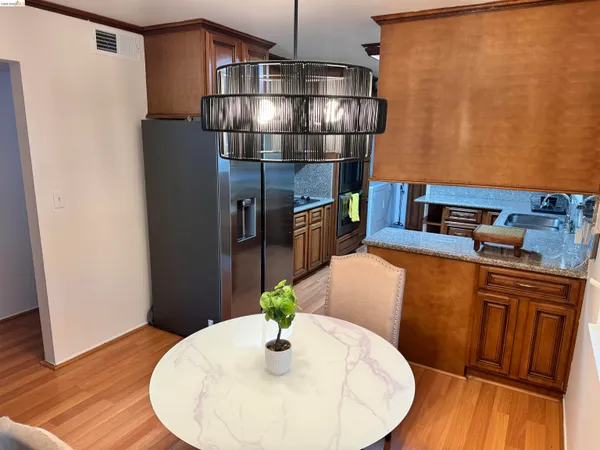 a kitchen with stainless steel appliances granite countertop a dining table chairs and wood floor