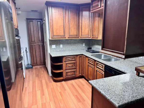 a kitchen with stainless steel appliances granite countertop wooden cabinets a refrigerator and dishwasher