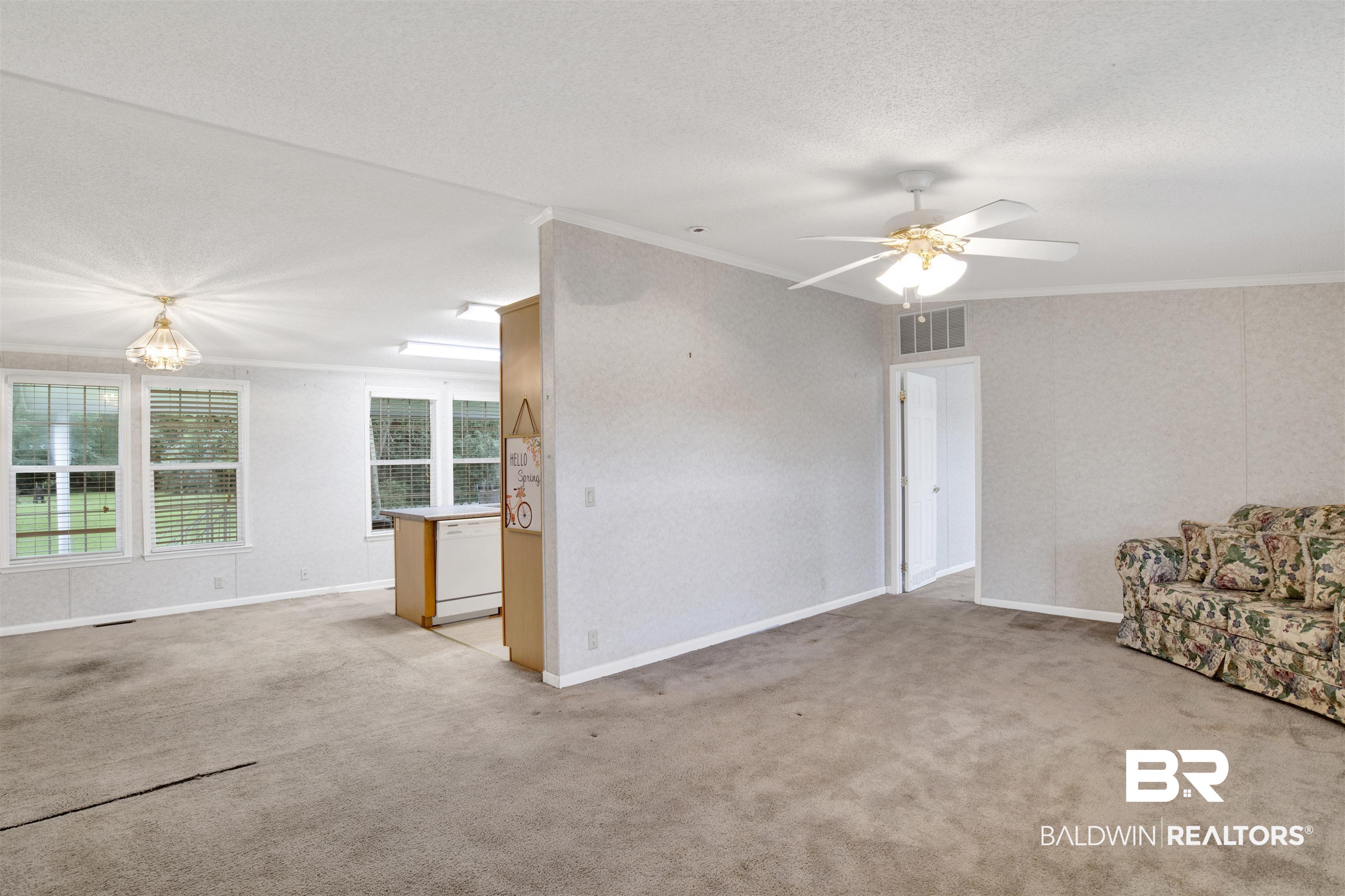 25700 County Road 71 Robertsdale, AL 36567 - Photo 6 of 40 Unfurnished living room featuring crown molding, light carpet, a textured ceiling, and a ceiling fan
