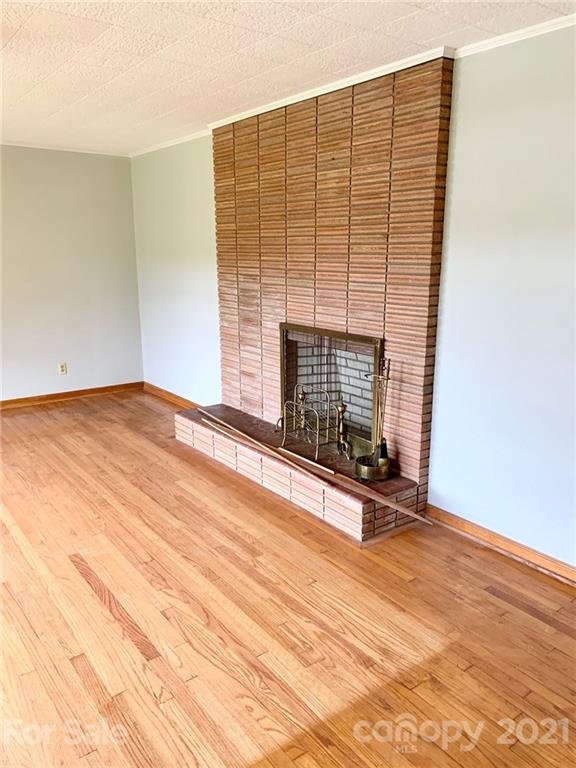 379 South Goforth Road Ferguson, NC 28624 - Photo 5 of 16 an empty room with wooden floor and fireplace