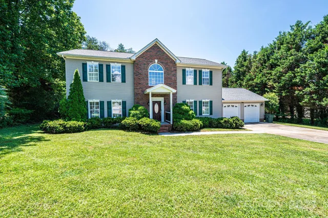 a front view of a house with a yard and trees