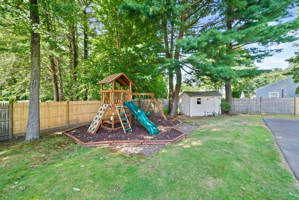 54 Birchcroft Road Canton, MA 02021 - Photo 12 of 37 a view of a backyard with a slide trees and wooden fence