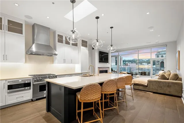 a kitchen with stainless steel appliances granite countertop a stove a sink a dining table and chairs with wooden floor