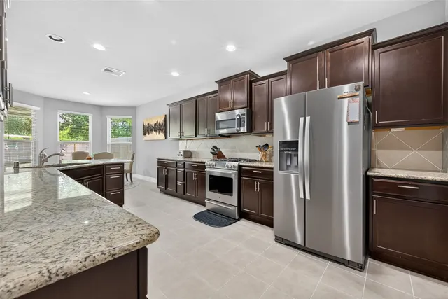 a kitchen with stainless steel appliances granite countertop a refrigerator a stove a sink a oven and a refrigerator