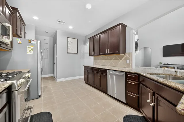 a kitchen with stainless steel appliances granite countertop a stove a sink and a microwave