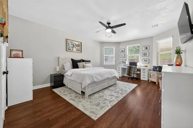 a spacious bedroom with a large bed a chandelier and windows