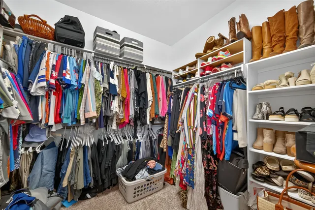 a view of walk in closet with clothes and shoes
