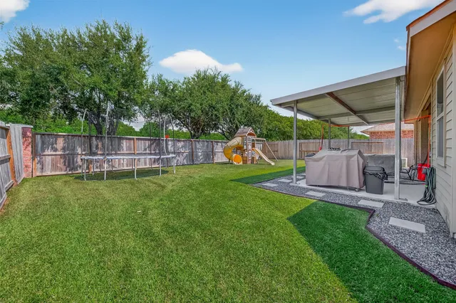a view of a backyard with table and chairs a fire pit and grass