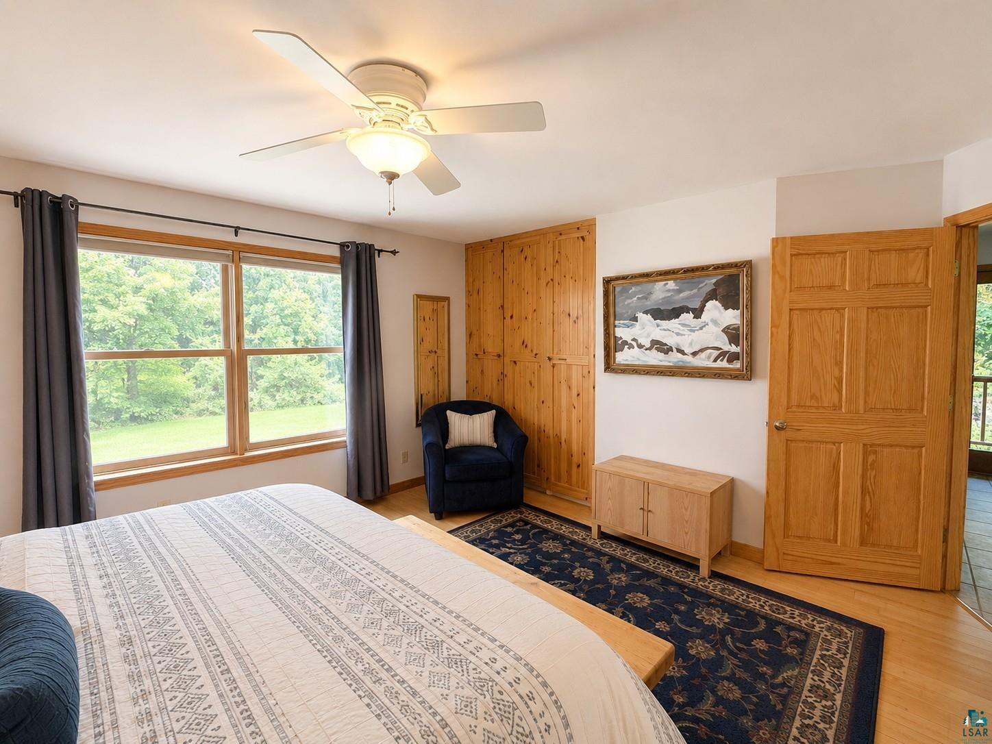 1787 North Bay Road Ely, MN 55731 - Photo 17 of 40 Bright room featuring wood-finish flooring, a ceiling fan, and a large window overlooking natural scenery