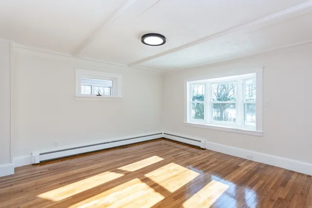 a view of a big room with wooden floor and windows