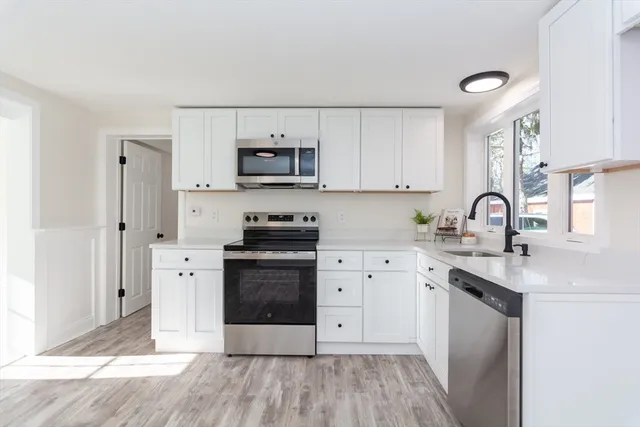 a kitchen with stainless steel appliances a sink cabinets and wooden floor
