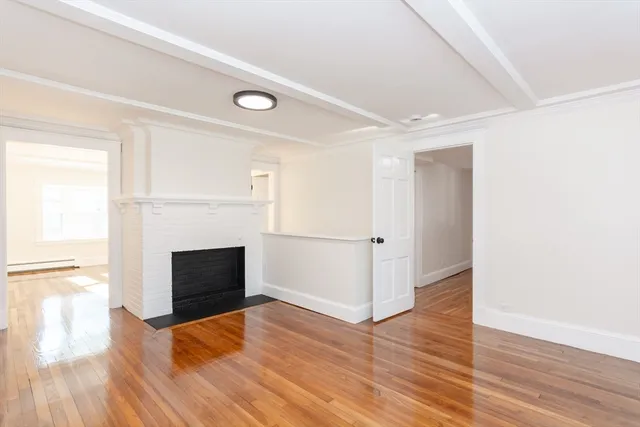 an empty room with wooden floor fireplace and windows