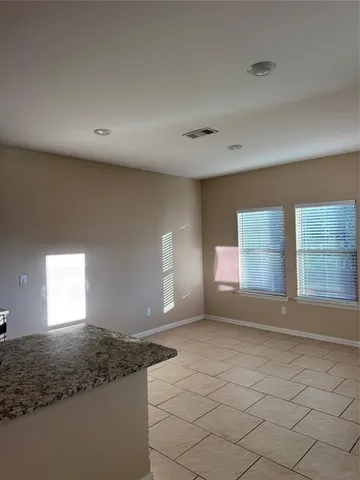 an empty room with wooden floor chandelier fan and windows