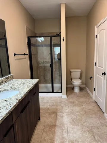 a bathroom with a granite countertop sink a toilet and a shower