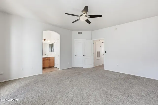 an empty room with closet and ceiling fan