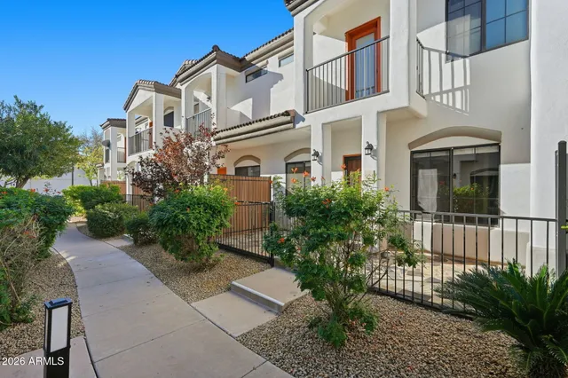 a front view of a multi story residential apartment building with yard and parking space