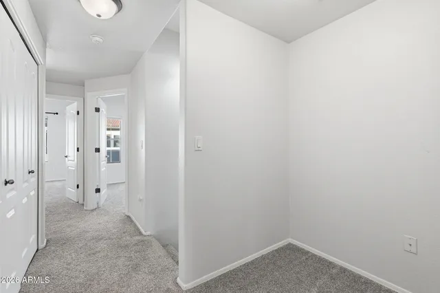 a view of an empty room with a window and chandelier fan