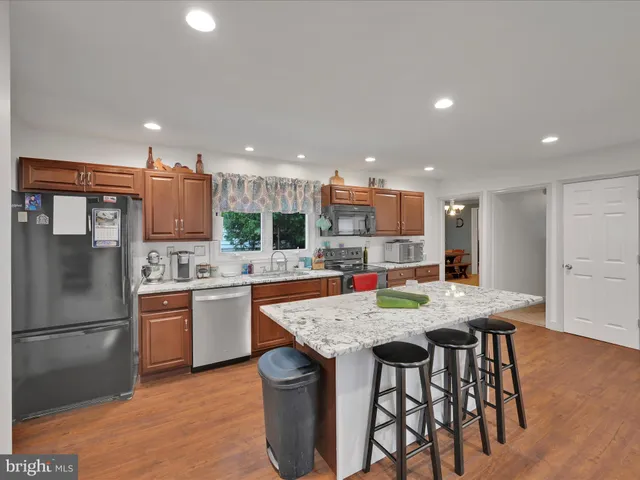 a kitchen with stainless steel appliances granite countertop a kitchen island a stove and a refrigerator with wooden floor