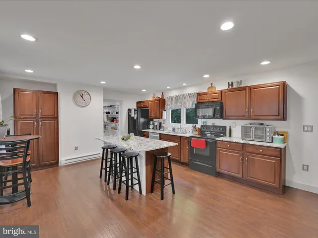 a open kitchen with stainless steel appliances granite countertop a refrigerator a stove top oven and a dining table with wooden floor