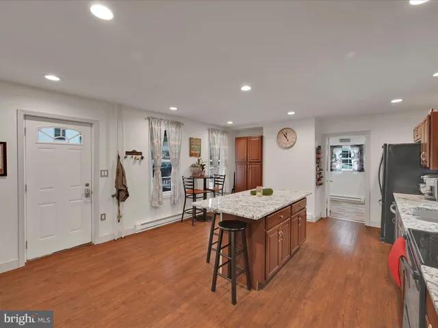 a living room with stainless steel appliances kitchen island granite countertop furniture and a wooden floor