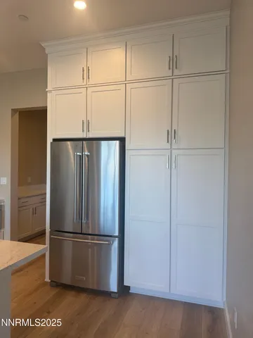 a view of a refrigerator in kitchen and white cabinets