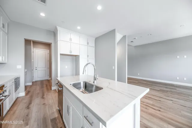 a kitchen with a sink a refrigerator and wooden floor