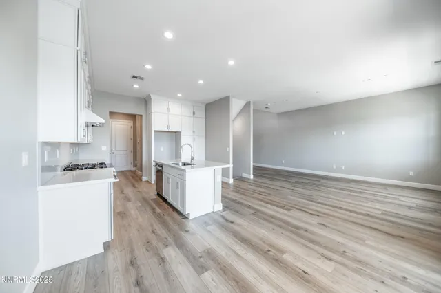 a large kitchen with a center island wooden floor stainless steel appliances and cabinets