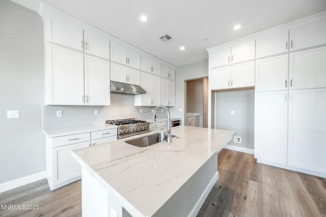 a kitchen that has a lot of white cabinets and stainless steel appliances
