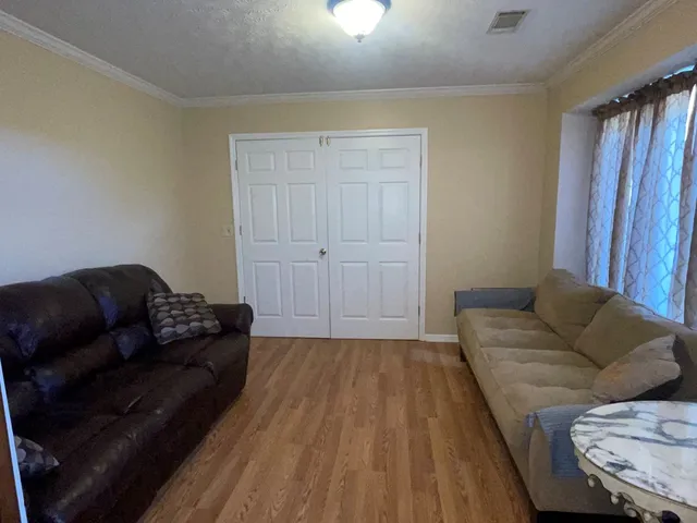 an empty room with wooden floor closet and windows