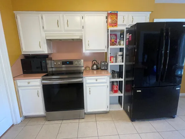 a kitchen with stainless steel appliances kitchen island granite countertop a refrigerator a stove a sink a dining table and chairs