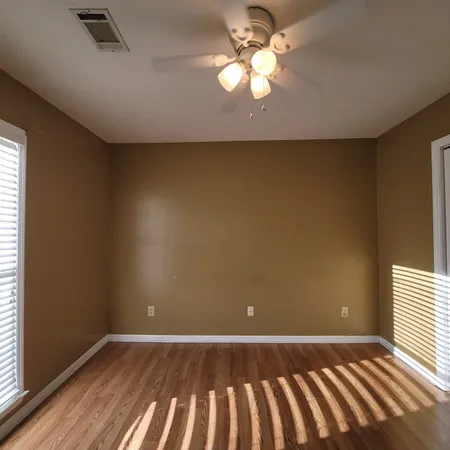 a view of an empty room with window and wooden floor