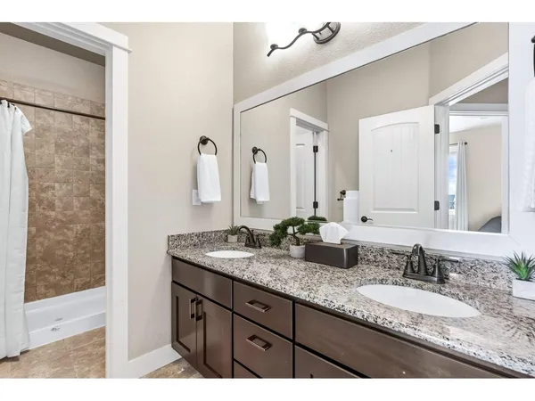 a bathroom with a granite countertop double vanity sink and a mirror