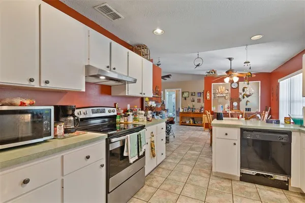 a large white kitchen with stainless steel appliances granite countertop a stove and cabinets