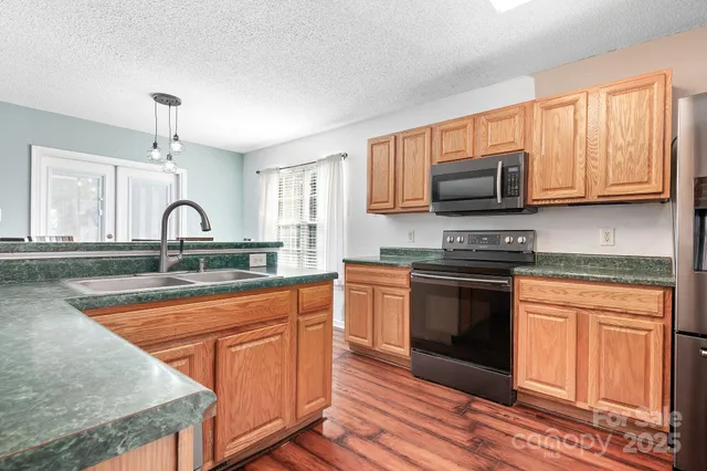 a kitchen with stainless steel appliances granite countertop a stove a sink and a microwave