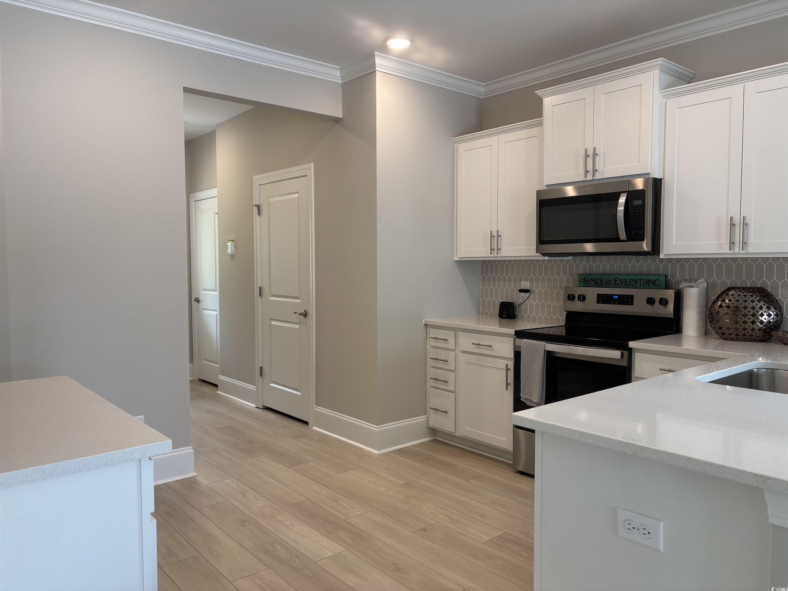 3125 Tiger Tail Road Conway, SC 29526 - Photo 8 of 37 Kitchen with stainless steel appliances, light countertops, white cabinetry, backsplash, and ornamental molding