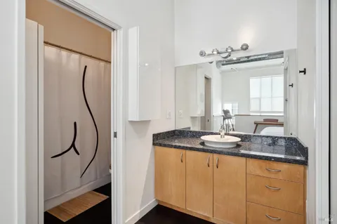 a bathroom with a granite countertop sink a mirror and a shower