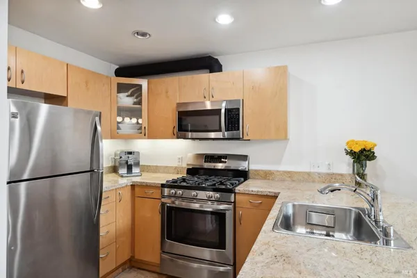 a kitchen with stainless steel appliances granite countertop a refrigerator stove a sink and a microwave