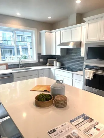 a large kitchen with kitchen island a large window and stainless steel appliances