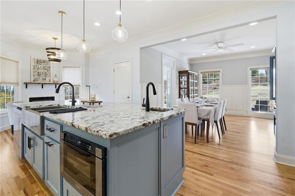 217 Wild Turkey Ridge Ball Ground, GA 30107 - Photo 21 of 55 a kitchen with granite countertop a stove a sink a dining table and chairs with wooden floor