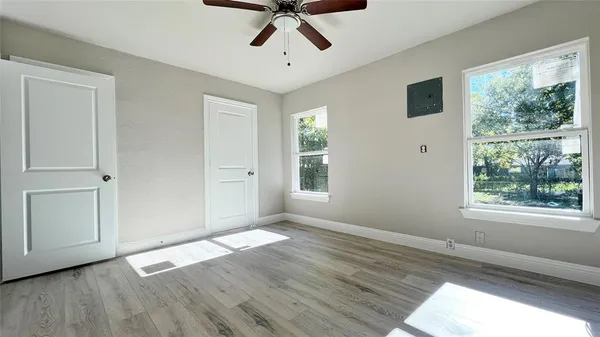 a view of empty room with wooden floor and fan