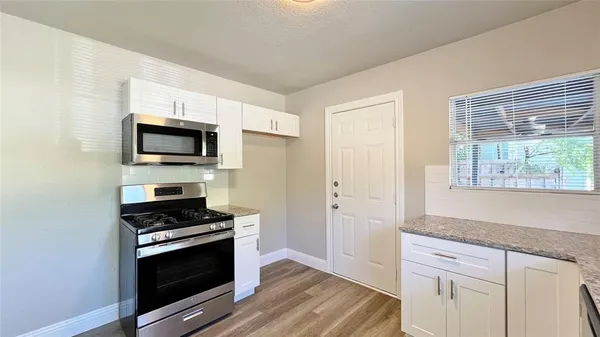 a kitchen with cabinets stainless steel appliances and wooden floor