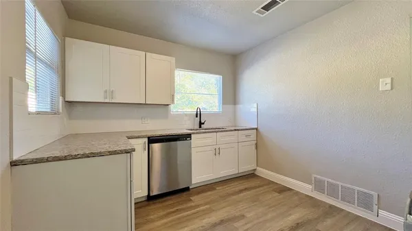 a kitchen with granite countertop white cabinets and a hard wood floor