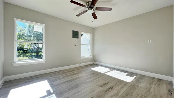 a view of empty room with wooden floor and fan