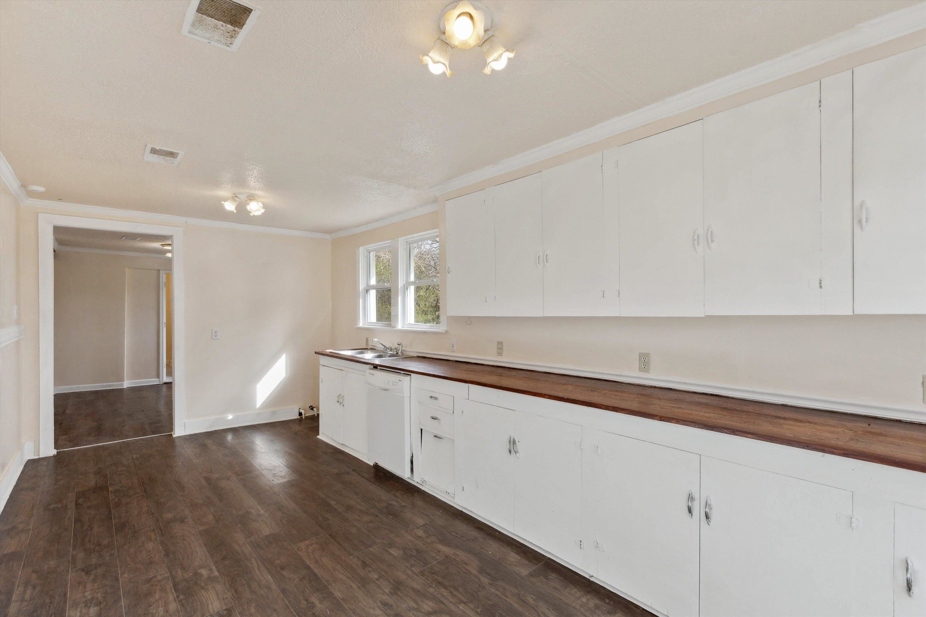 8457 East Kerrville Rosemark Road Millington, TN 38053 - Photo 17 of 32 Kitchen with butcher block counters, dark wood-type flooring, crown molding, white cabinets, and white dishwasher