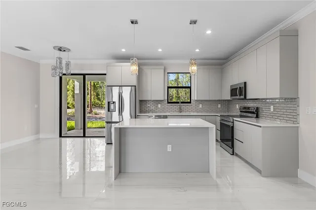 a large kitchen with stainless steel appliances kitchen island granite countertop a refrigerator and a stove top oven