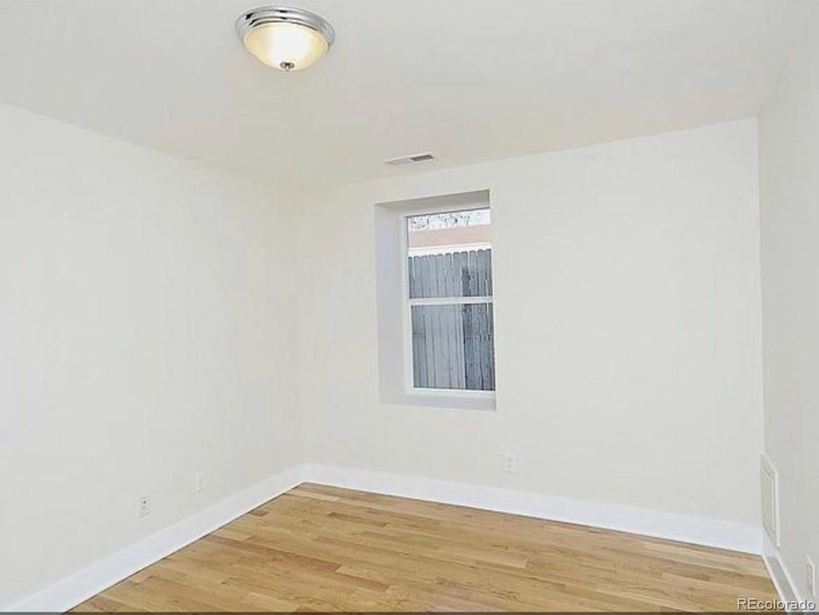 3217 Lawrence Street Denver, CO 80205 - Photo 11 of 13 an empty room with wooden floor and windows