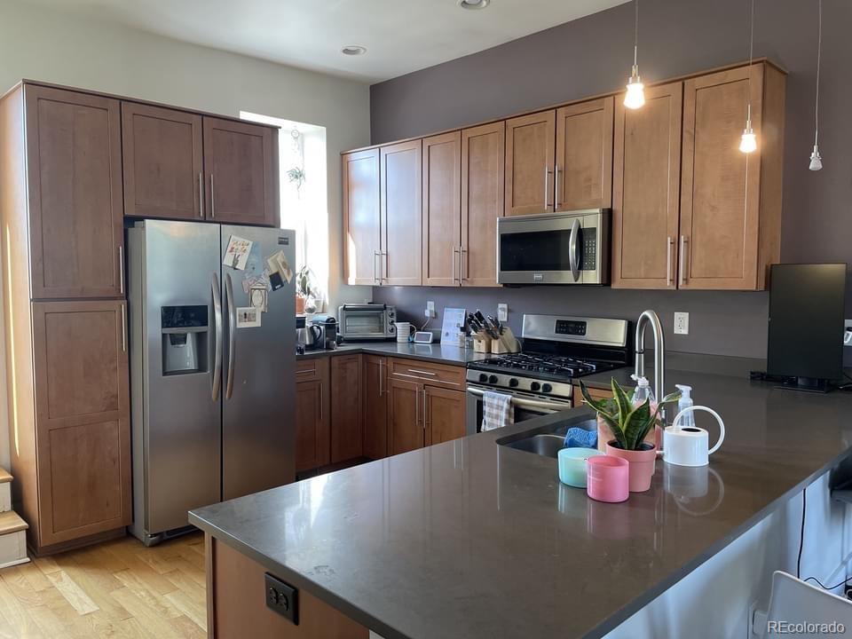3217 Lawrence Street Denver, CO 80205 - Photo 8 of 13 a kitchen with stainless steel appliances granite countertop a refrigerator a stove a sink cabinets and a dining table
