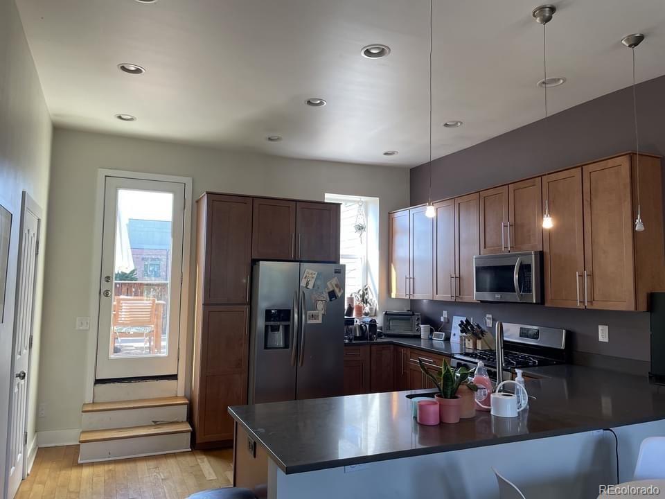 3217 Lawrence Street Denver, CO 80205 - Photo 9 of 13 a kitchen with stainless steel appliances granite countertop a sink refrigerator and microwave